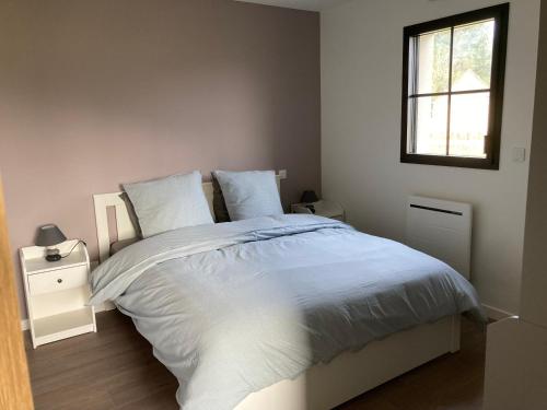 マレスヴィルにあるLes Petites Maisons dans la Prairie - 1の白いシーツと窓のあるベッドのある寝室