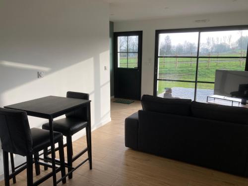 un salon avec un canapé noir et une table dans l'établissement Les Petites Maisons dans la Prairie - 1, à Maresville