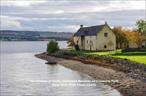 an old house on the shore of a body of water at Foulis Castle Gate Lodge in Evanton