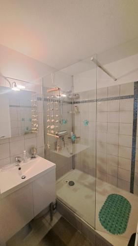 La salle de bains est pourvue d'une douche en verre avec un lavabo et une douche. dans l'établissement PAMPLEMOUSSE 2 - Appartement avec piscine, vue mer, proche golf, à Saint-Jean-de-Monts