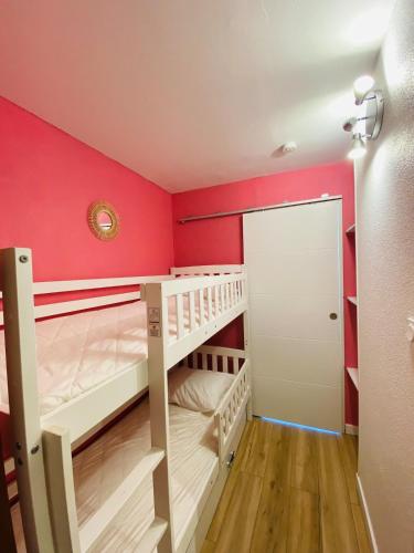 Cette chambre comprend 2 lits superposés et un mur rouge. dans l'établissement Studio sur plage avec piscine et balcon vue mer, à Saint Cyprien Plage