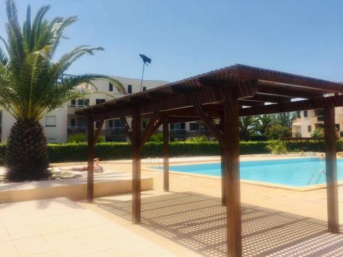 un pavillon en bois devant une piscine dans l'établissement Studio sur plage avec piscine et balcon vue mer, à Saint Cyprien Plage