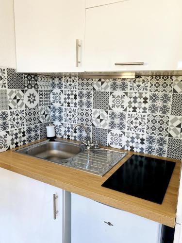 - une cuisine avec un évier et un mur en carrelage dans l'établissement Studio sur plage avec piscine et balcon vue mer, à Saint Cyprien Plage