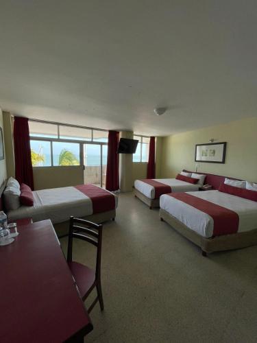 a hotel room with three beds and a table at Hotel Royalty in Veracruz
