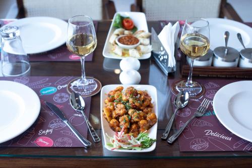 a table with plates of food and glasses of wine at Astra Resort and Caffe in Kasauli