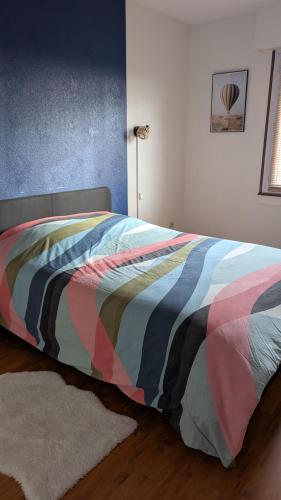 - un lit avec une couette colorée dans une chambre dans l'établissement Joli appartement proche gare, à Molsheim