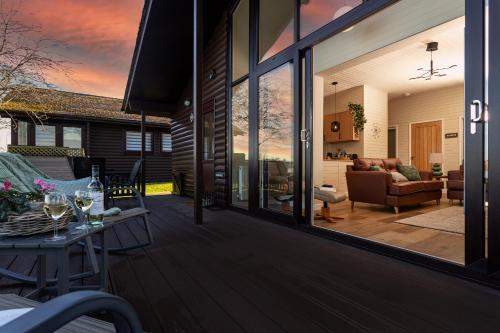 a porch with glass doors and a living room at Sandmartin Lodge a lakeshore haven at Pine Lake Resort in Carnforth