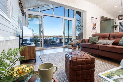 a living room with a couch and a large window at Sandmartin Lodge a lakeshore haven Pine Lake Resort in Carnforth