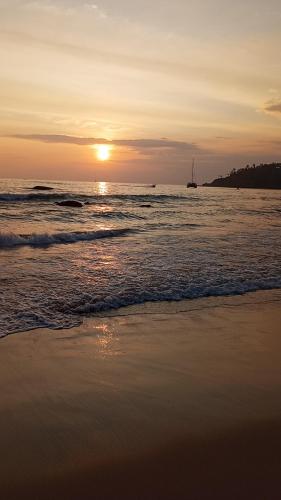 a sunset on the beach with a boat in the water at Bisandu guesthouse in Mirissa