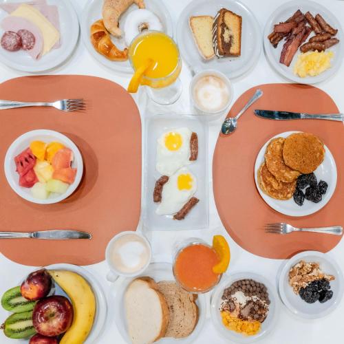 a table topped with plates of breakfast foods and eggs at Holiday Inn Rosario by IHG in Rosario