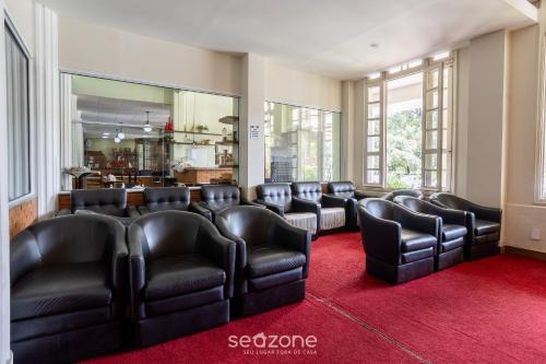 a waiting room with black leather chairs and a red carpet at Lindo Condomínio com Lazer em Poços de Caldas - QUI in Poços de Caldas