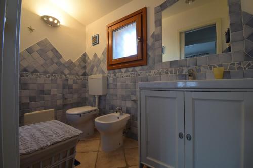 a bathroom with a toilet and a sink and a mirror at Bellissima villa piscina 8 pax 1500 mt dal mare FMP-CAT01-PI in Monte Petrosu