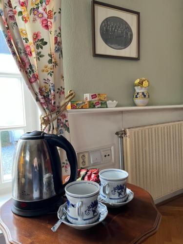a tea kettle and two cups on a table at U Pešků in Kožlí u Orlíka