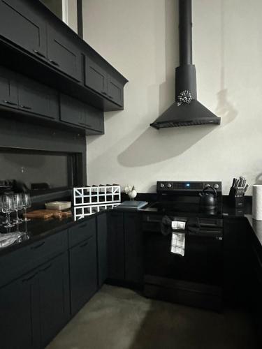 a kitchen with black cabinets and a stove top oven at Black Sheep Hideaway Modern Countryside Serenity in Clermont