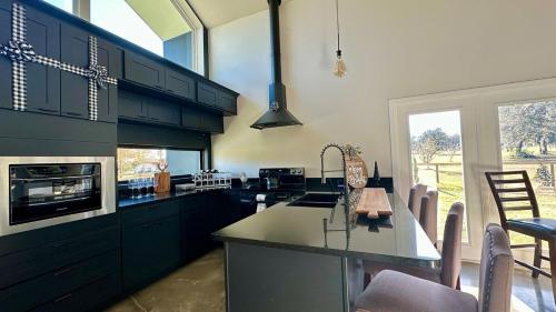a kitchen with black cabinets and a kitchen island with chairs at Black Sheep Hideaway Modern Countryside Serenity in Clermont