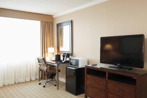 a hotel room with a flat screen tv and a desk at Ethan Allen Hotel in Danbury