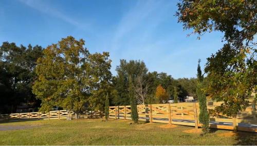a wooden fence in front of a field with trees at Black Sheep Hideaway Modern Countryside Serenity in Clermont