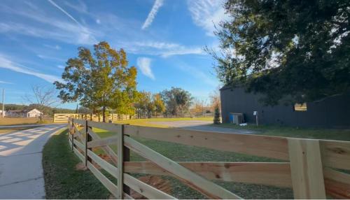 a wooden fence next to a road with a barn at Black Sheep Hideaway Modern Countryside Serenity in Clermont