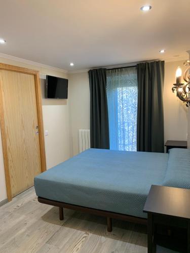 a bedroom with a blue bed and a window at Hostal Milana Girona in Girona
