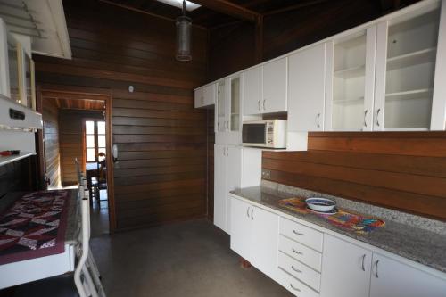 una cucina con mobili bianchi e un forno a microonde di CASA DE MADEIRA a Conselheiro Lafaiete