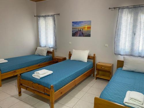 a room with three beds with blue sheets at Nefeli House in Loutsa