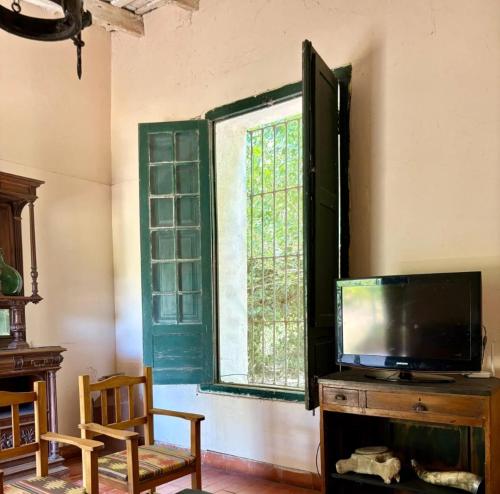Una sala de estar con televisión y una ventana. en Chacra del Molino, en Navarro