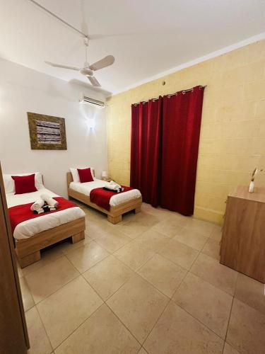 a room with two beds and a red curtain at Kewkba Holiday Home in Kerċem