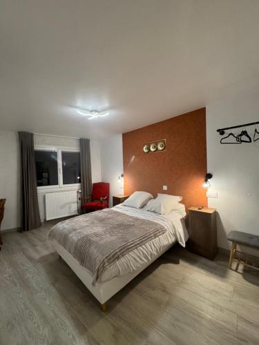 une chambre avec un grand lit et une chaise rouge dans l'établissement Le Napoléon, à Corps