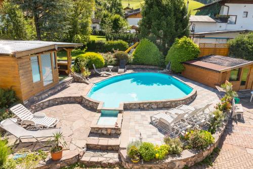 una piscina en un patio trasero con sillas y cenador en Appartements Jochum, en Niederau