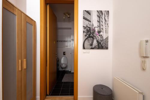 La salle de bains est pourvue de toilettes et d'une photo de vélo sur le mur. dans l'établissement Praha 2, à Prague