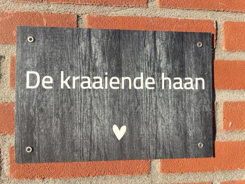 a sign on a brick wall with the words de karaderha ham at De kraaiende haan in Liessel
