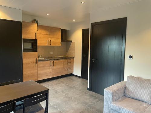 a kitchen with wooden cabinets and a table and a chair at De kraaiende haan in Liessel