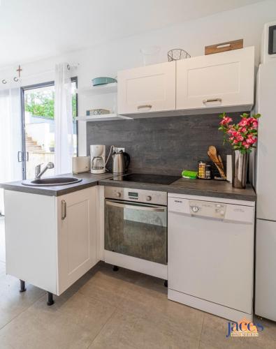 une cuisine avec des armoires blanches et des appareils électroménagers blancs dans l'établissement Villa Paradis Pyla sur Mer, à La Teste-de-Buch