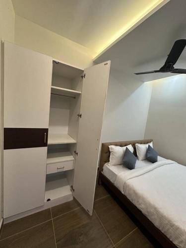 a bedroom with a bed and white walls and shelves at Serene Villa in Puducherry