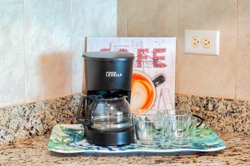 a coffee maker sitting on a counter next to glasses at El Combate Condos, Enjoy Ocean Views and Pool Fun in Boqueron