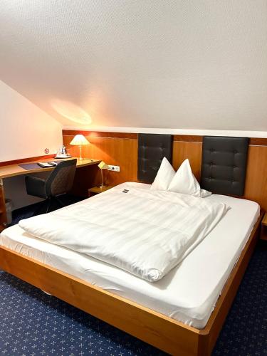 a large bed in a room with a desk at Hotel Hubertus Gernsheim Rhein in Gernsheim
