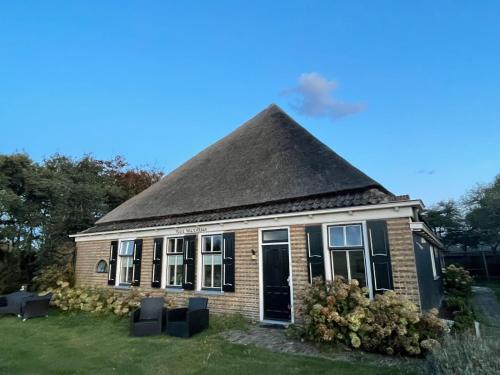 a small brick house with a black roof at BenB Hoeve Weltevreden in De Westen