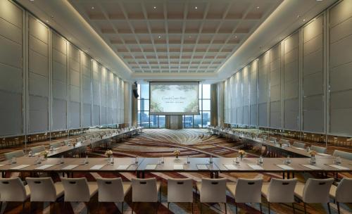 a large room with tables and chairs in front of a screen at Grande Centre Point Lumphini Bangkok in Bangkok