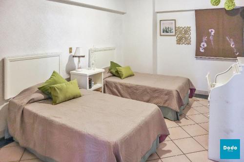 a hotel room with two beds with green pillows at Departamento en Mazatlán a 5 minutos de la playa in Mazatlán