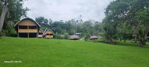 a building on a hill with a green field and trees at Puri Ma'u Beach & Bungalows in Boba