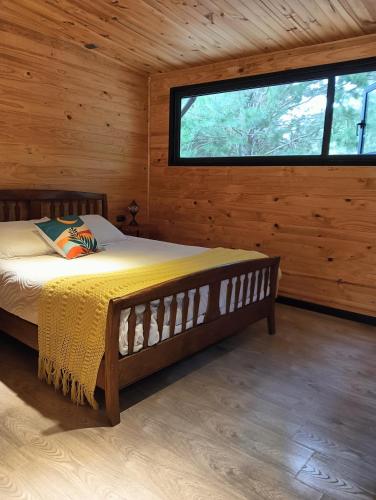 a bedroom with a bed in a wooden cabin at Refugio Silvestre Parque Nacional Siete Tazas-Salida a río y pesca in El Bolsico