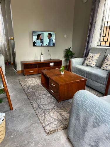 ein Wohnzimmer mit einer Couch und einem Fernseher an der Wand in der Unterkunft Nana Apartment in Marombosa