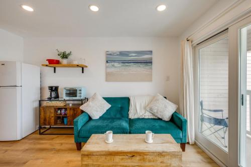 a living room with a green couch and a table at Steps to Beach Corpus Christi Condo with Balcony in Corpus Christi