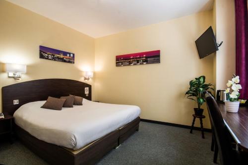 a hotel room with a large bed and a desk at Hôtel Notre Dame in Bordeaux