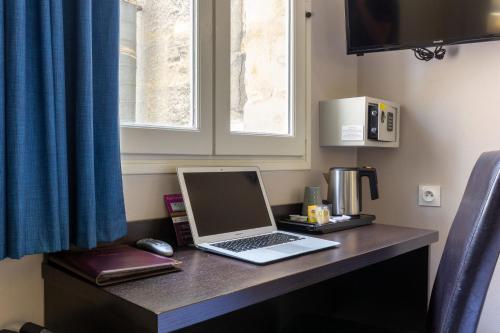 a laptop computer sitting on a desk in a room at Hôtel Notre Dame in Bordeaux