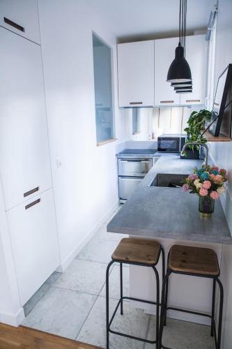 une cuisine avec des placards blancs et une table avec deux tabourets dans l'établissement A 5 minutes de la place de la nation, Studio, Paris, Rive Gauche, à Paris