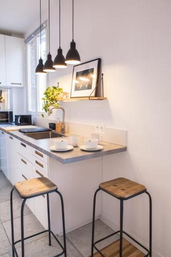 une cuisine avec deux tabourets de bar et un comptoir dans l'établissement A 5 minutes de la place de la nation, Studio, Paris, Rive Gauche, à Paris