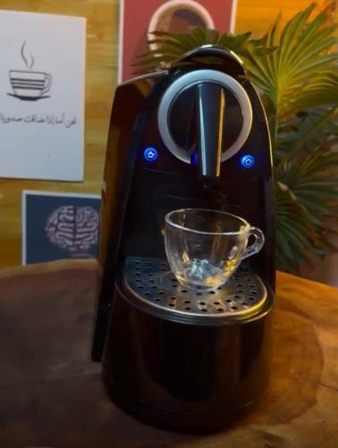a black coffee maker with a glass on a table at شقة أنوار مسقط in ‘Udhaybah