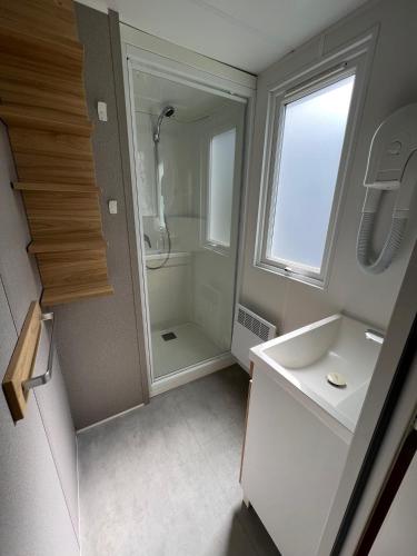 a white bathroom with a shower and a sink at Camping Les Payolles in Saint-Georges-dʼOléron