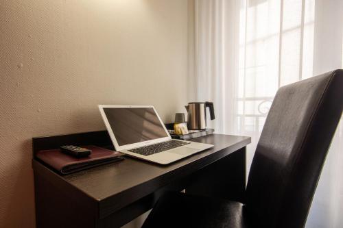 a laptop computer sitting on a desk next to a window at Hôtel Notre Dame in Bordeaux